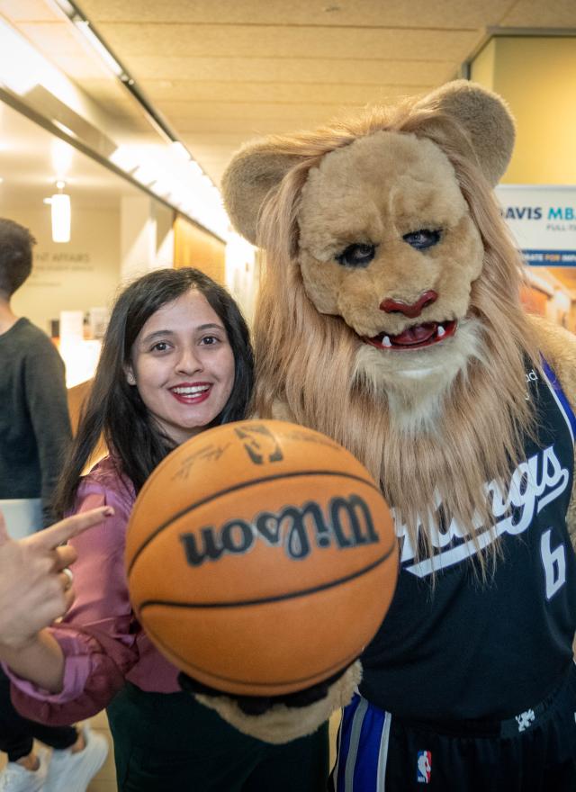 MBA student points to basketball held by Sacramento Kings Mascot Slamson