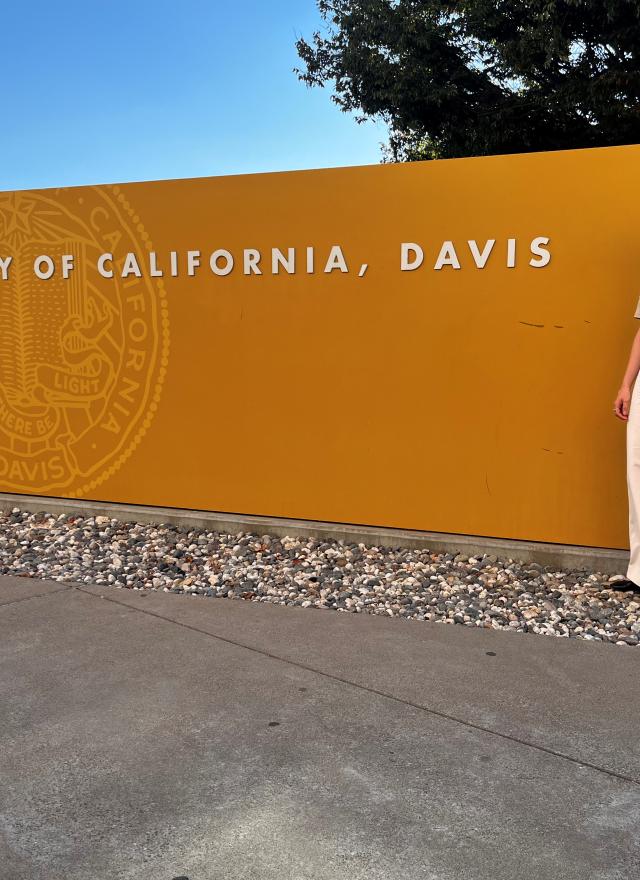 Daniela Mallard Juarez standing in front of a yellow UC Davis sign