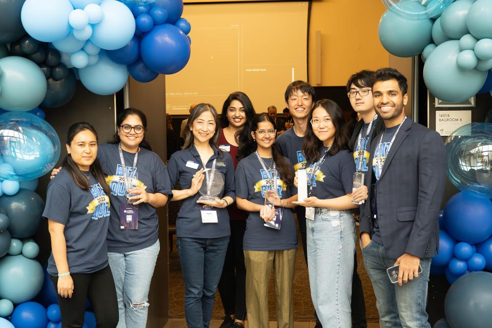 UC Davis team members hold up awards under a balloon arch