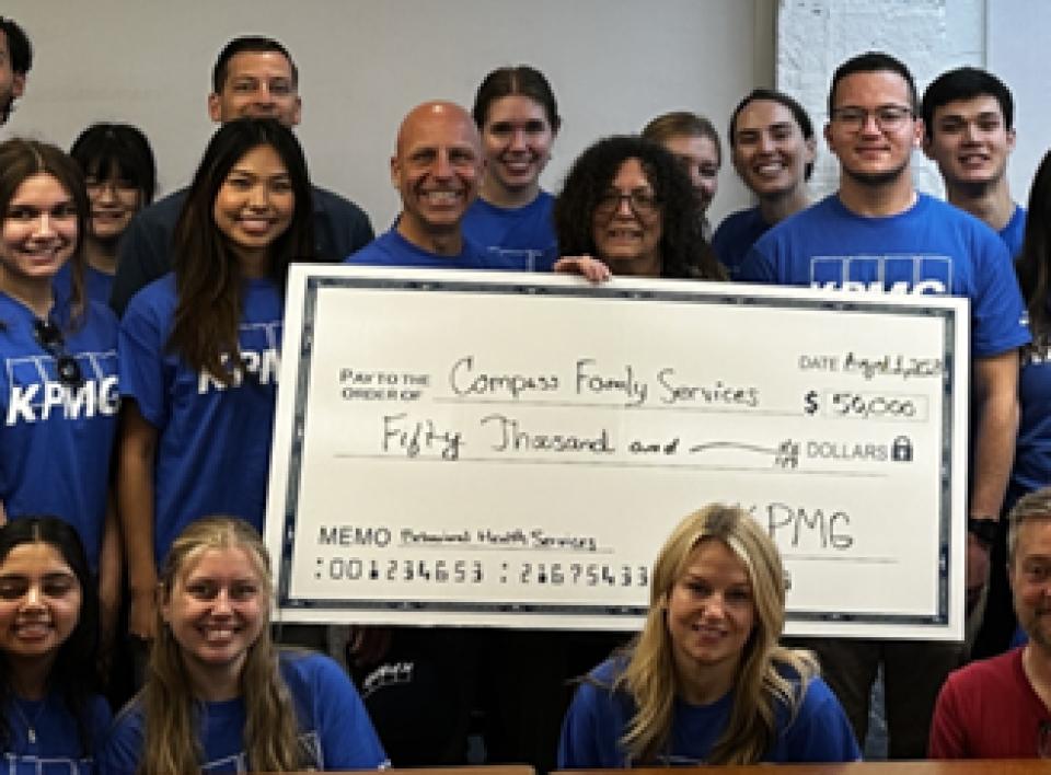 Kendall Richards in a group shot holding a giant check at the KPMG offices