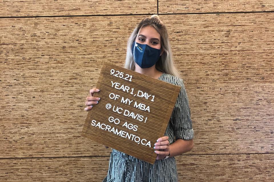 Leticia Garay MBA 24 holds a sign recognizing her first day of grad school