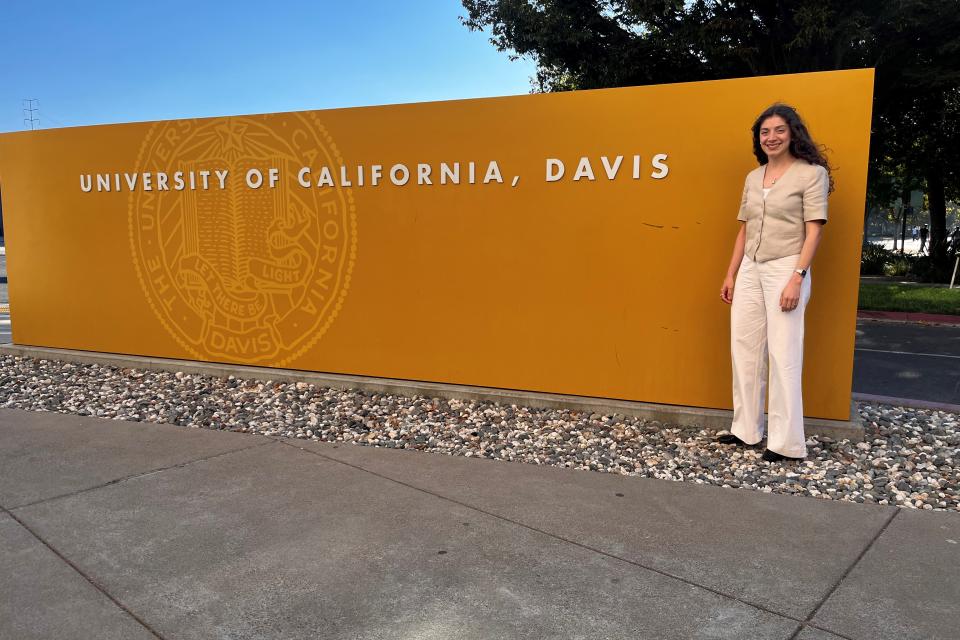 Daniela Mallard Juarez standing in front of a yellow UC Davis sign