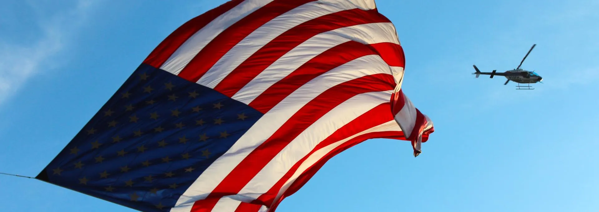 American Flag with a helicopter flying behind it