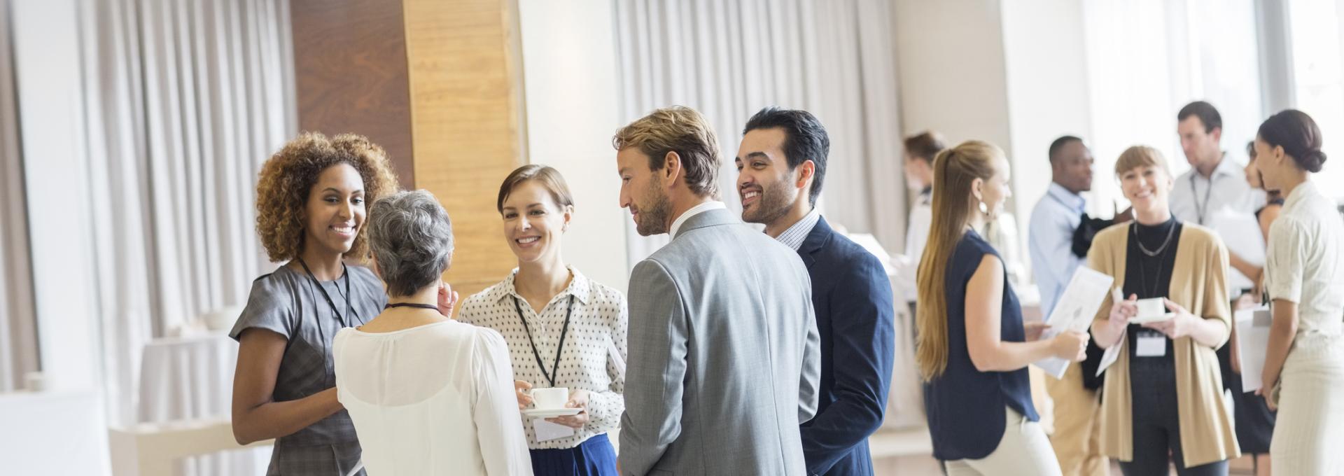 Group of business people standing in hall, smiling and talking together stock photo