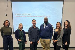 Liza Santa Ana and MBA students in front of a presentation screen