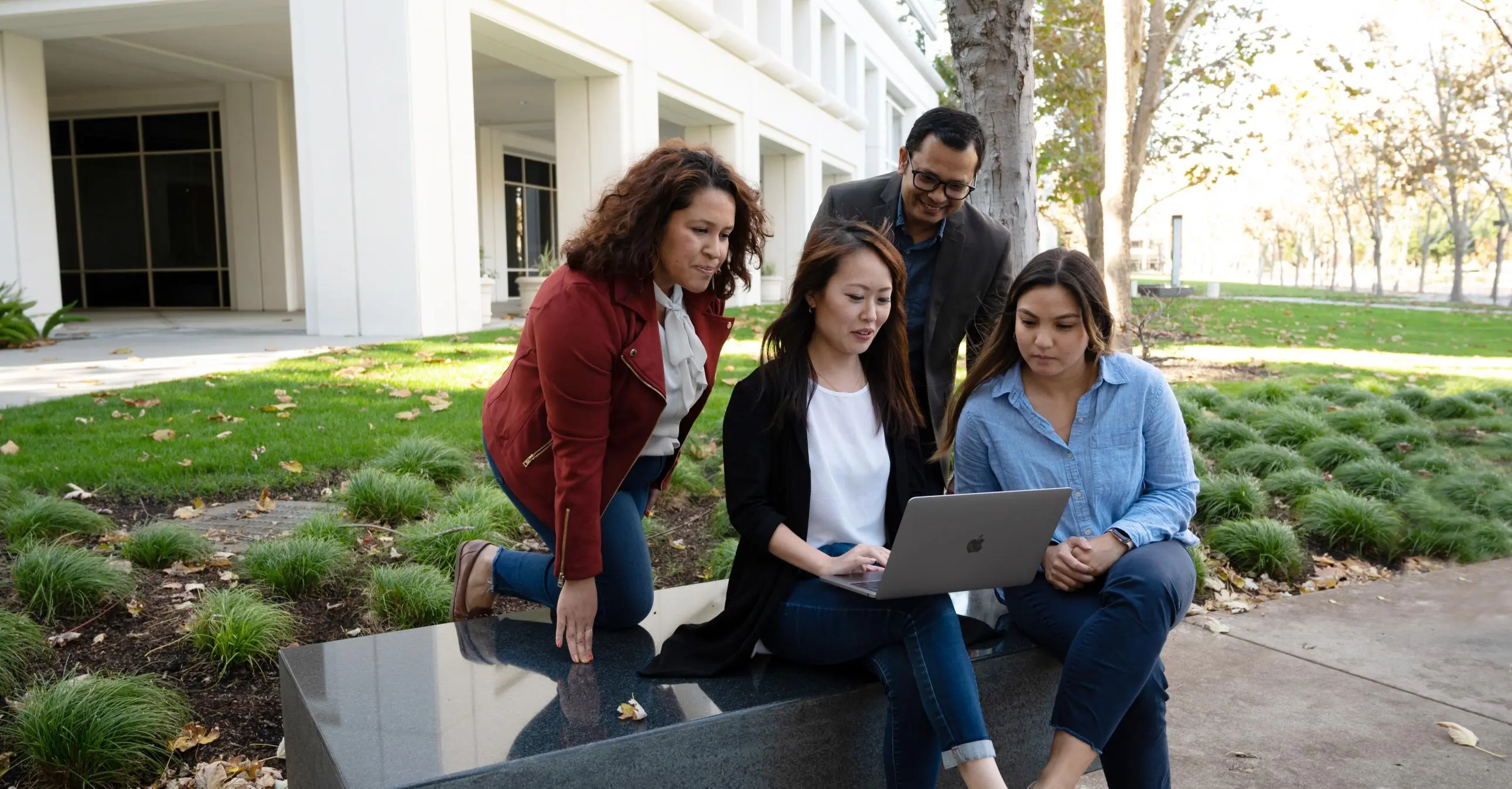 Group of diverse people gathered around a laptop at Bishop Ranch