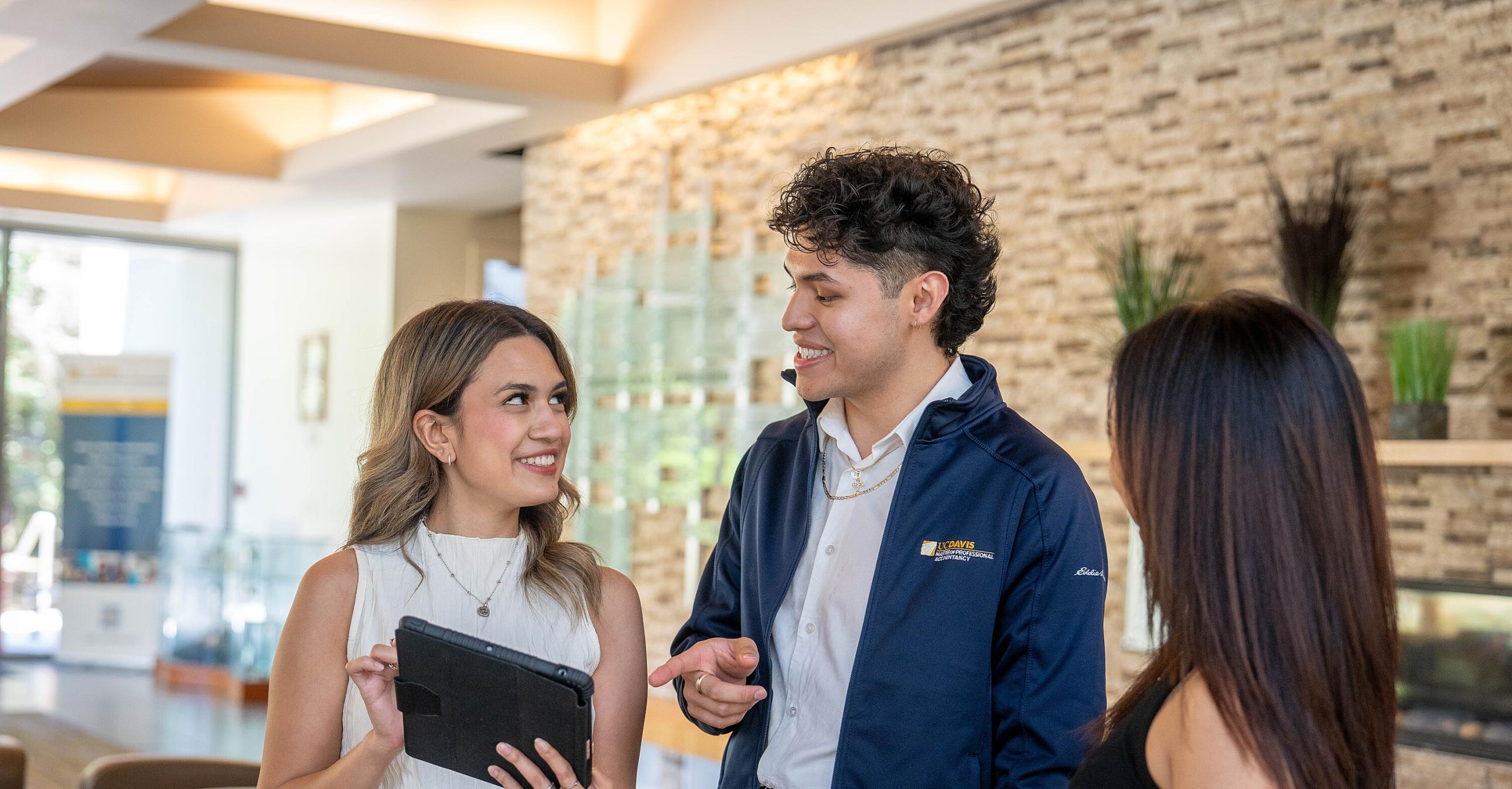 Three MPAc students talking in the Gallagher Hall lobby