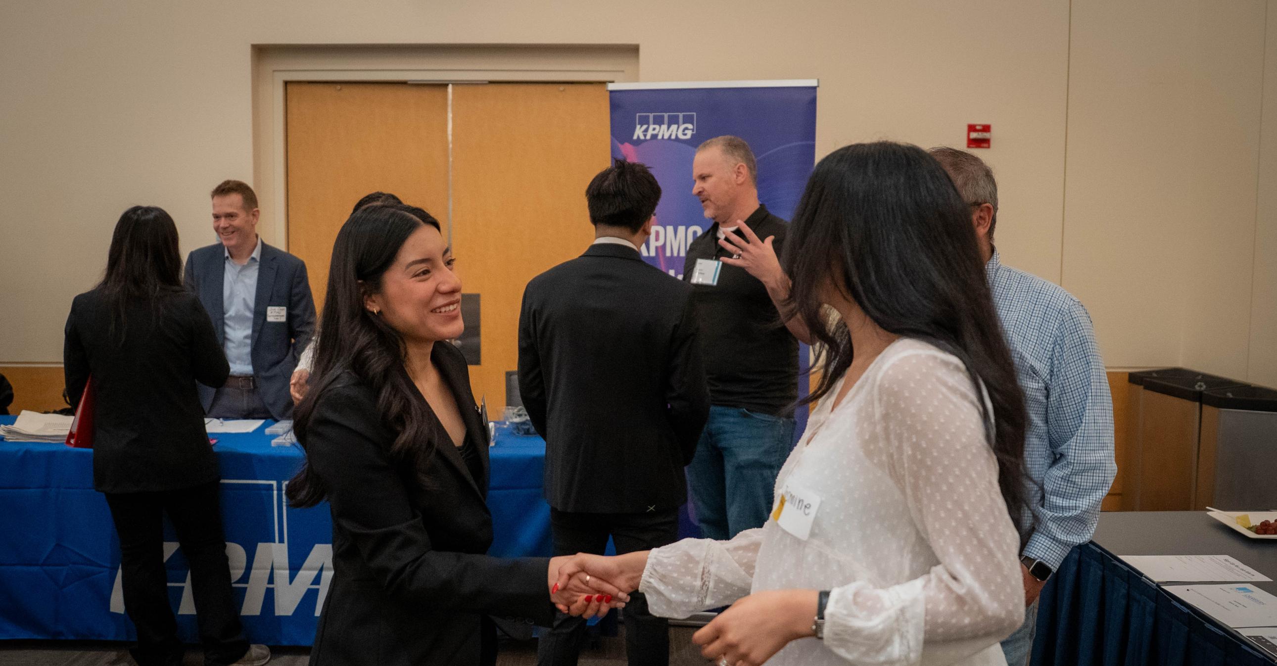 An MPAc student and a recruiter shake hands at the Meet the Firms event