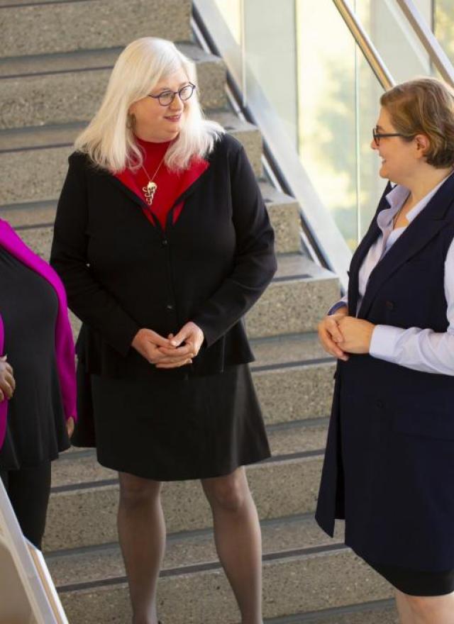 Three professionally dressed women chatting in a stairwell