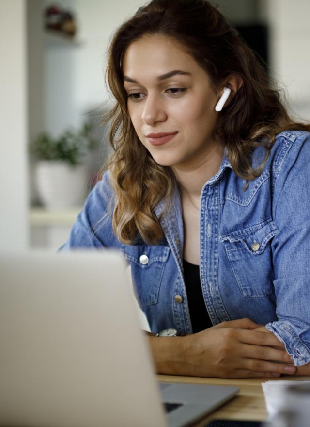 Young woman with bluetooth headphones having video conference at home