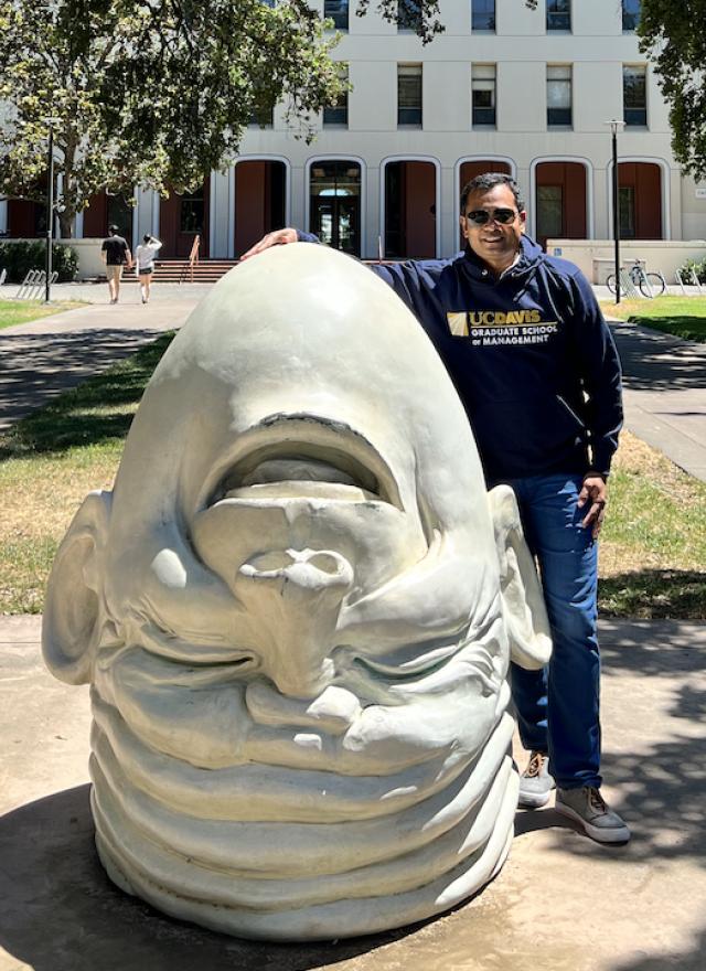 Debasish Panda at the UC Davis campus posing with an egghead sculpture