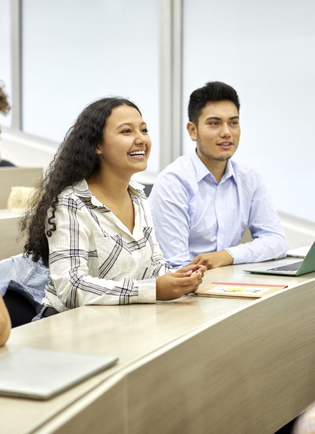 Three students sitting in a classroom smiling