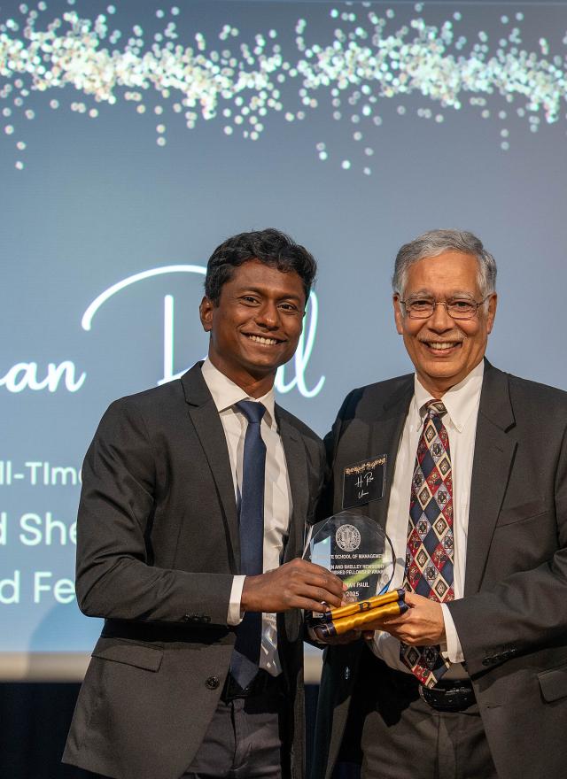 Roshan Paul holding an award on stage with Rao Unnava