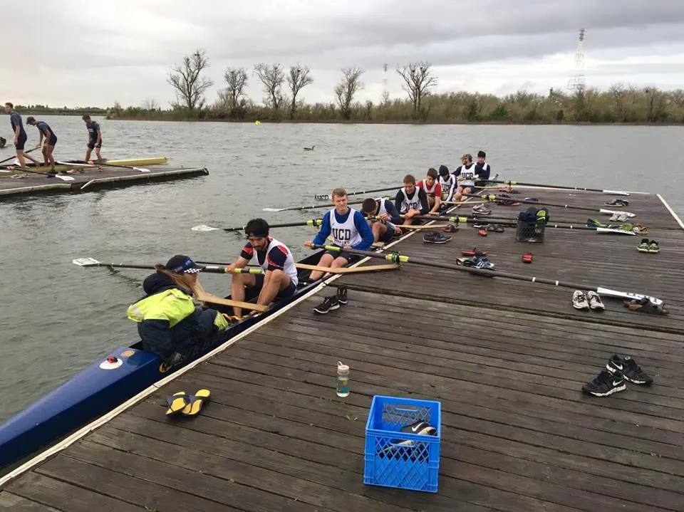 Rowers on a crew boat at a dock