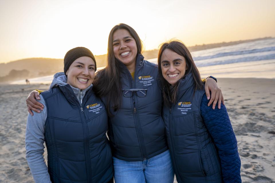 Three people on beach at sunset