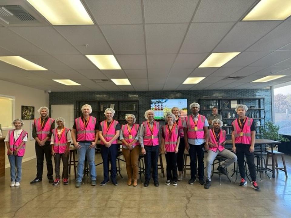 Group of people wearing pink safety vets and hair nets