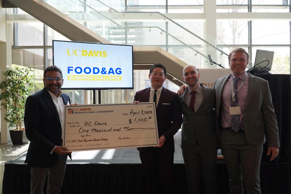 Judge Brijesh Krishnaswamy, president and global head spices of Ofi, presents a check for $1,000 to UC Davis MBA students Gordon Chang, Nathaniel Morrison and Lucas Haskins. 