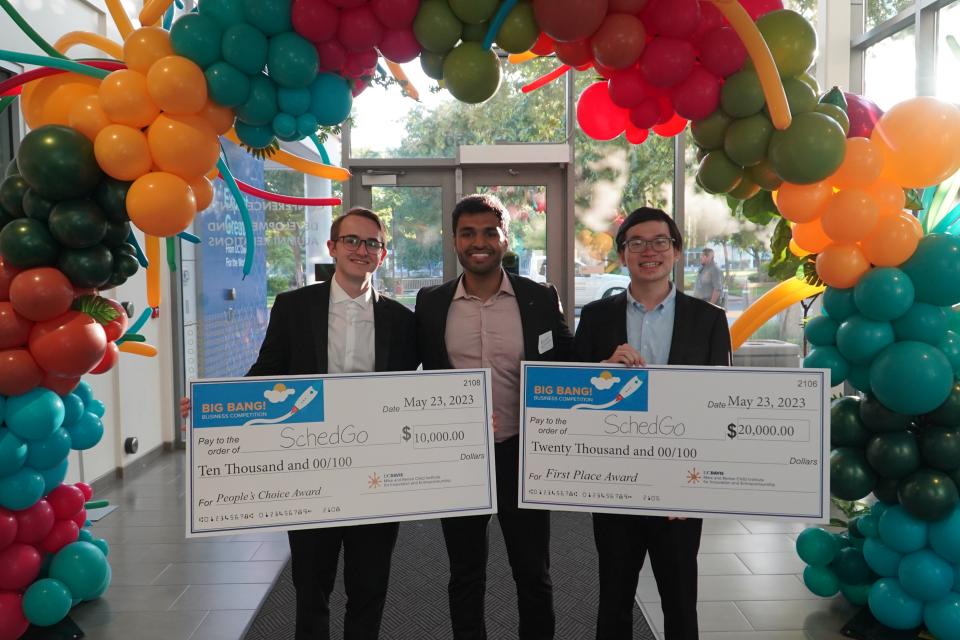 The 3-person SchedGo team hold up checks showing off their win