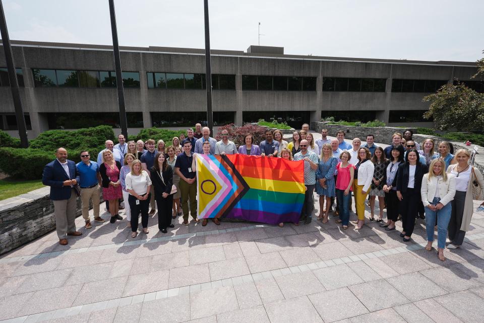 Alexandra von Klan holding a rainbow flag with a large group of her coworkers