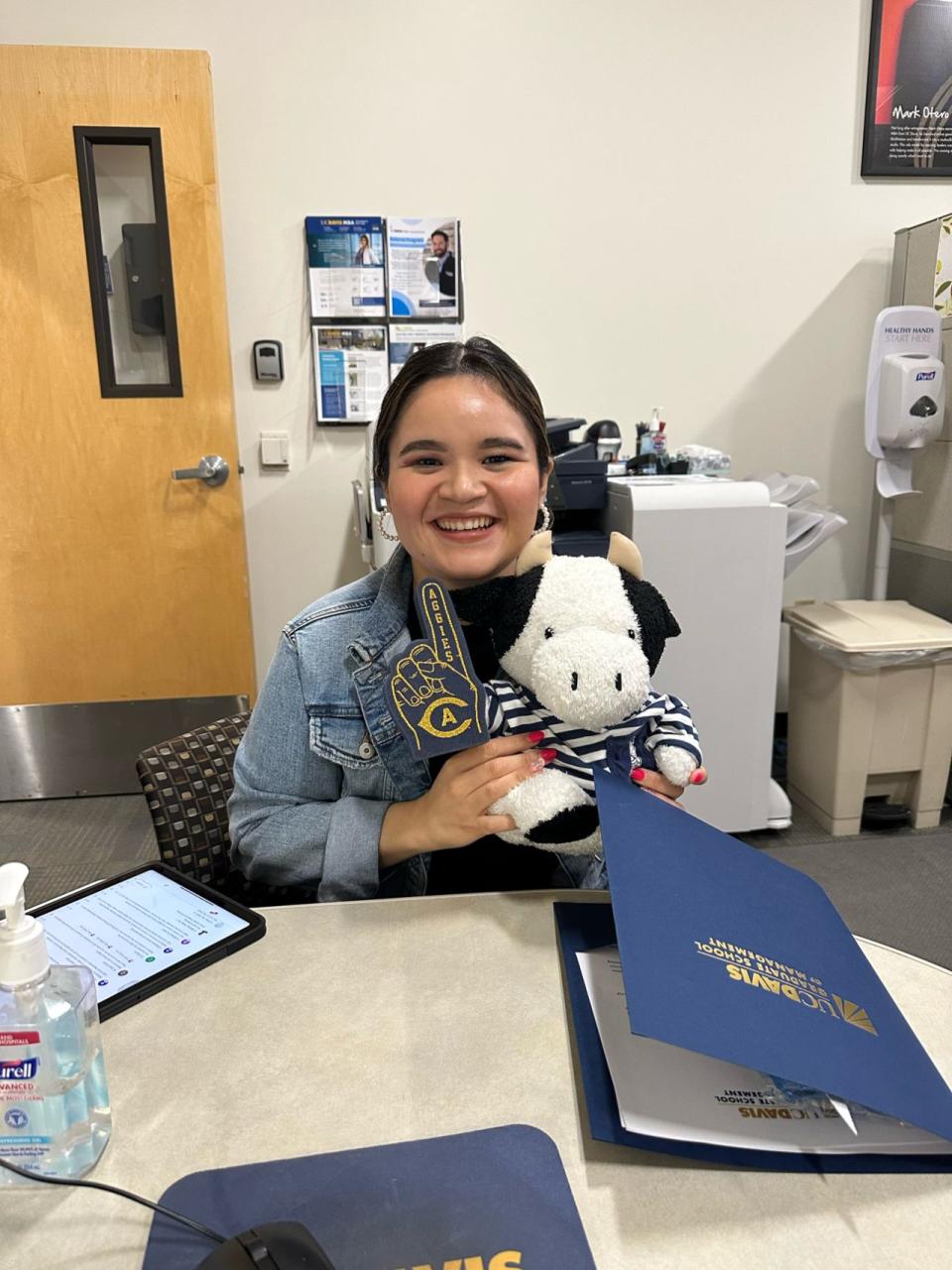 Marisol Ibarra holding up a stuffed cow as part of her UC Davis swag