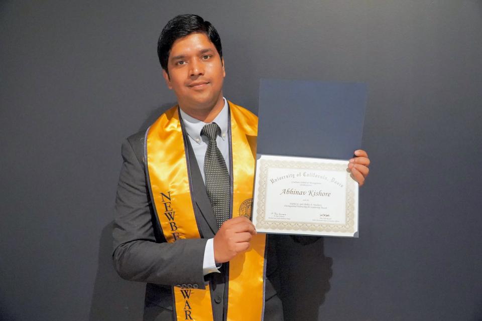 Abhinav Kishore holding up the the Stephen G. and Shelley A. Newberry Distinguished Fellowship Award