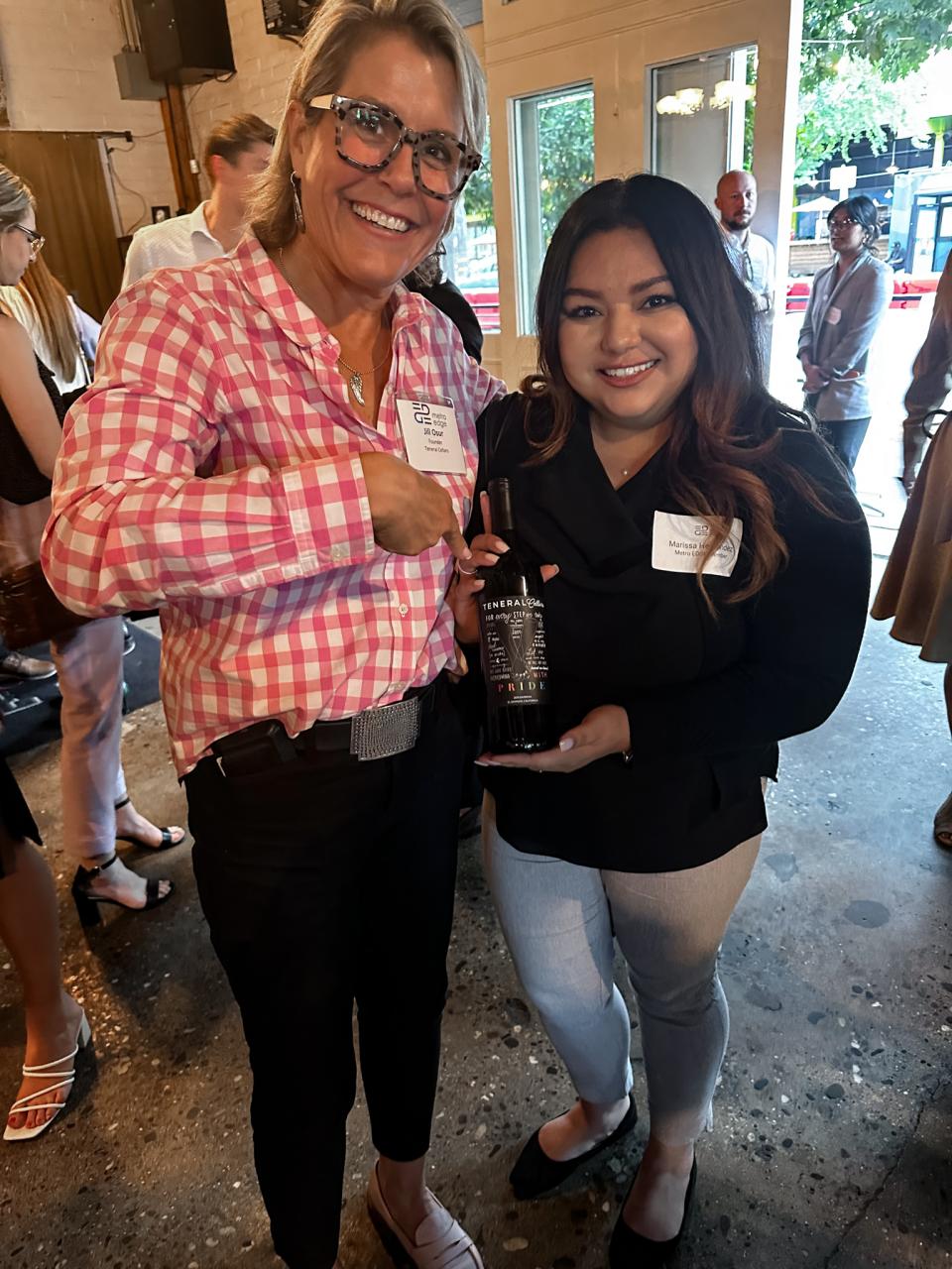 Marissa Hernandez and Jill Osur holding up a bottle of wine at the Executive Insight 2023 event