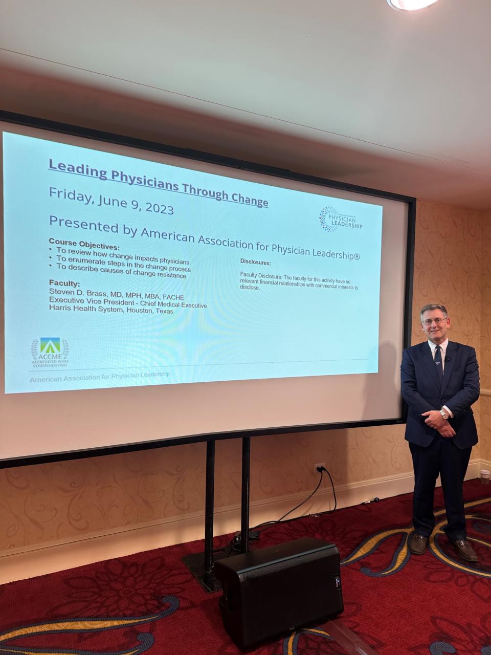 Dr. Steven Brass standing next to a display screen at a presentation