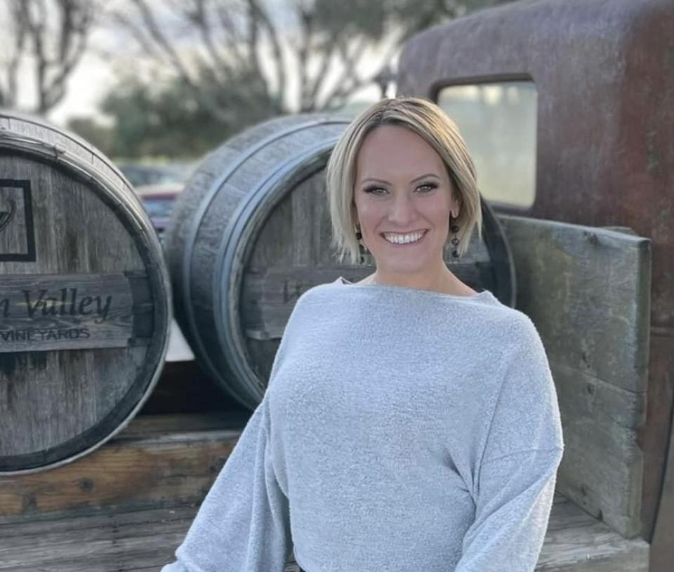 Natalie Frazier in front of wine barrels