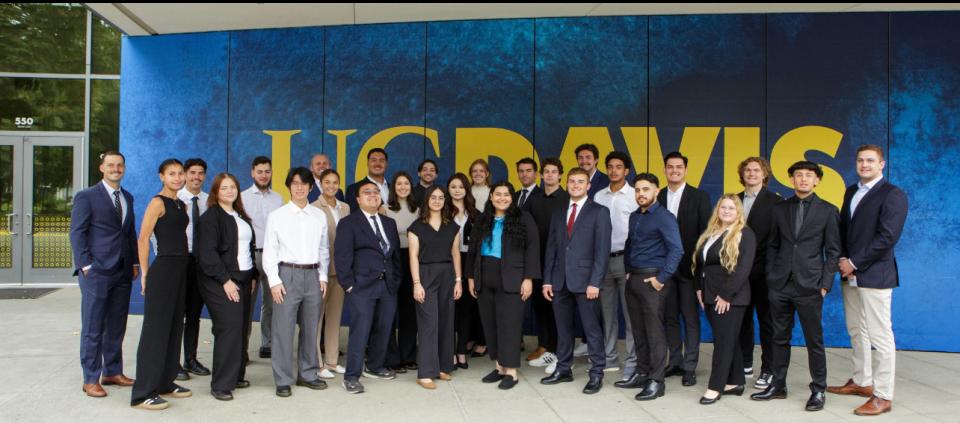 Alexis Rangel and her inaugural Master of Management cohort outside a blue UC Davis mural