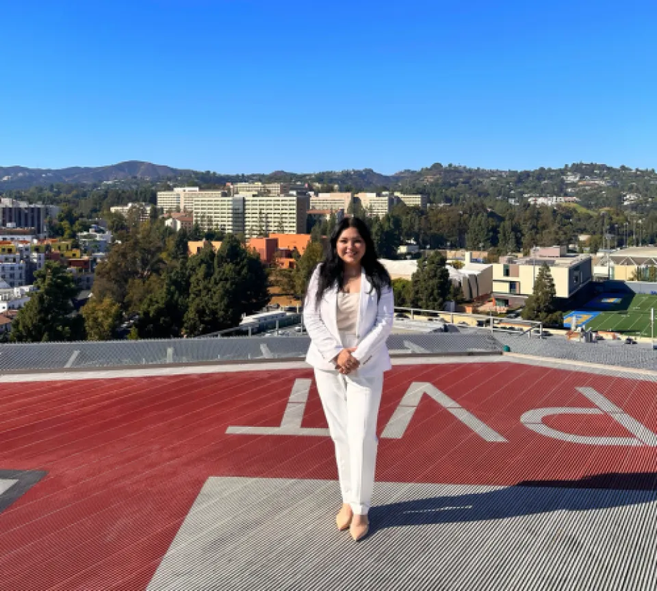 Marissa Hernandez standing on a helipad at UCLA Health with green hills and buildings in the background
