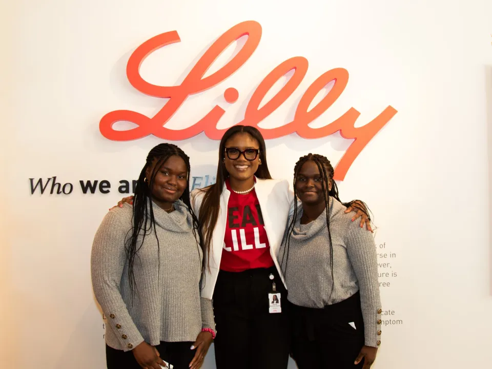Shaneil Mckenzie with mentees in front of Lilly logo