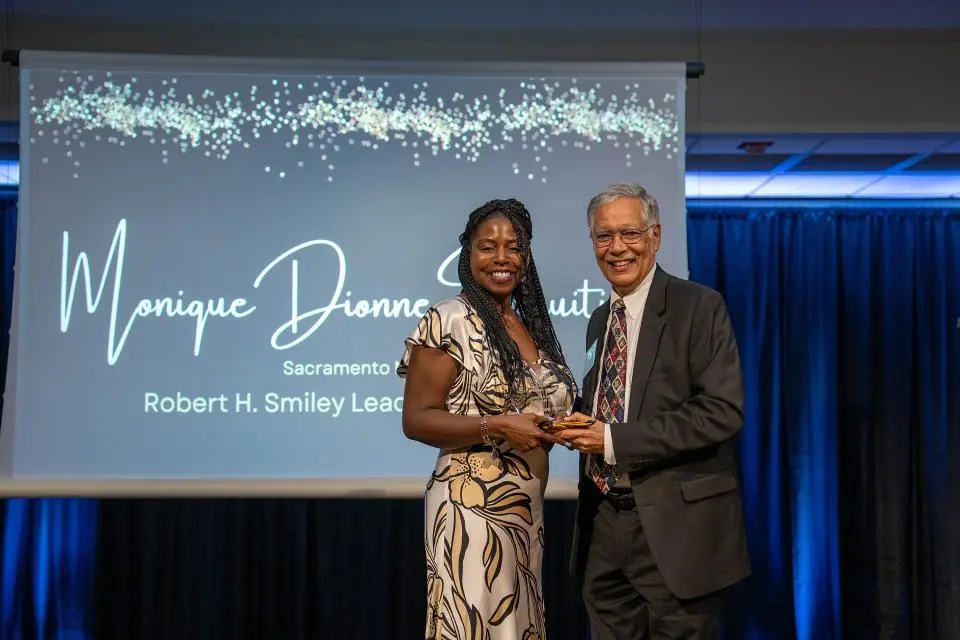 Monique Dionne Fruitier on-stage receiving award from Dean Rao Unnava
