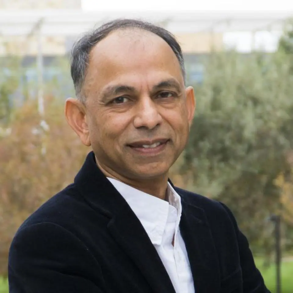 Hemant Bhargava wearing a dark blazer and white shirt, standing outdoors with greenery in the background.