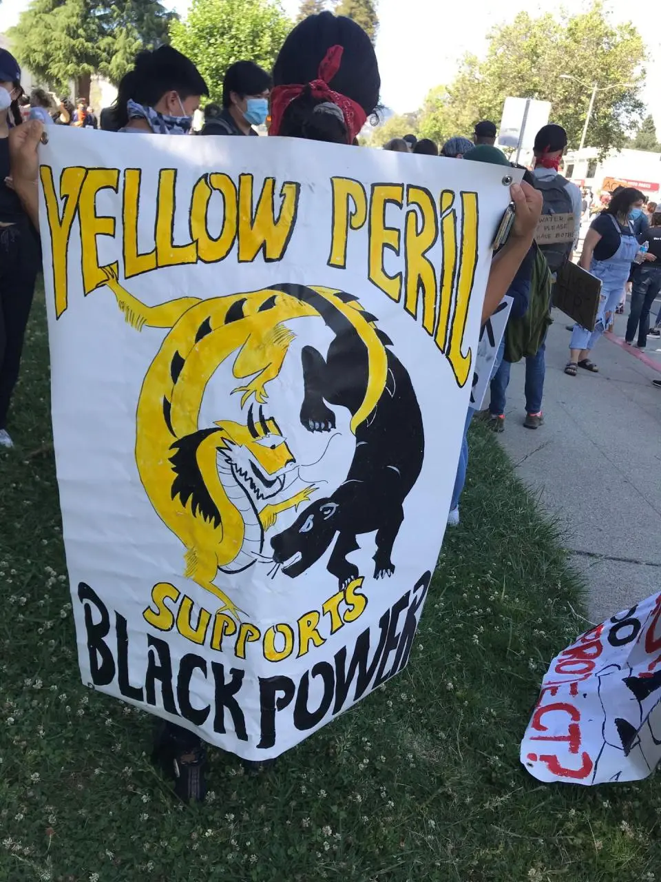 A protester in 2020 holding a sign reading "Yellow Peril Supports Black Power"