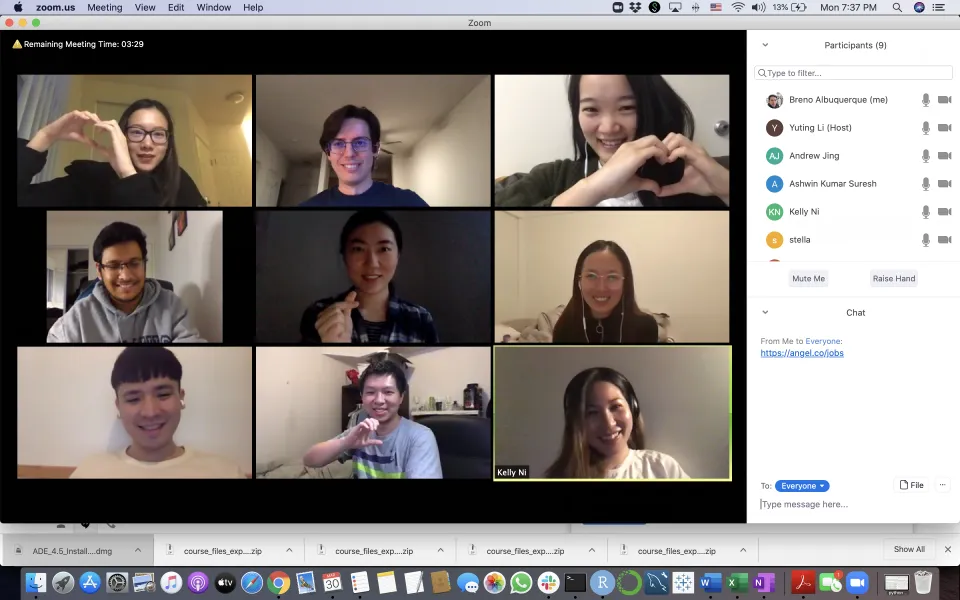 A Zoom video call with nine participants smiling, some making heart shapes with their hands; chat and participant list visible on the right.