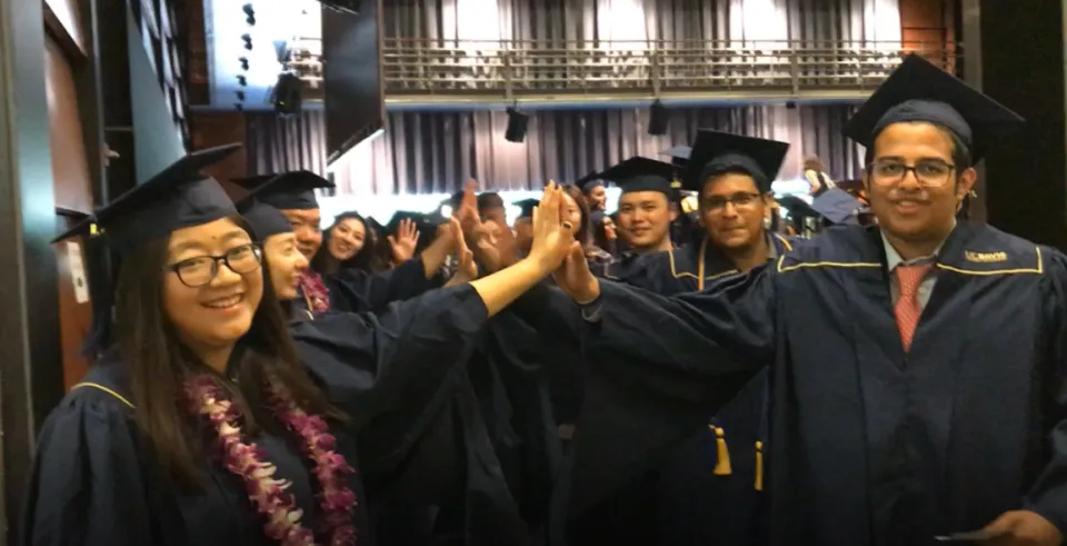 2019 MSBA graduates Liz Liu and Sheel Vora high-five prior to their commencement ceremony.