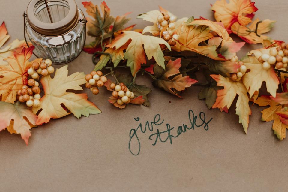 Give thanks written on table with fall leaves