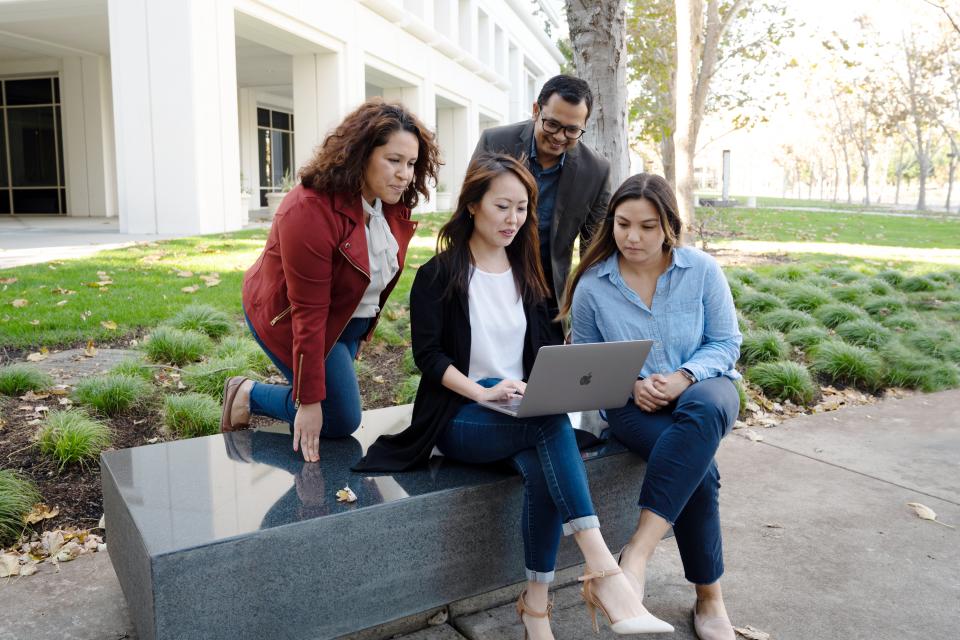 Group of diverse people gathered around a laptop at Bishop Ranch