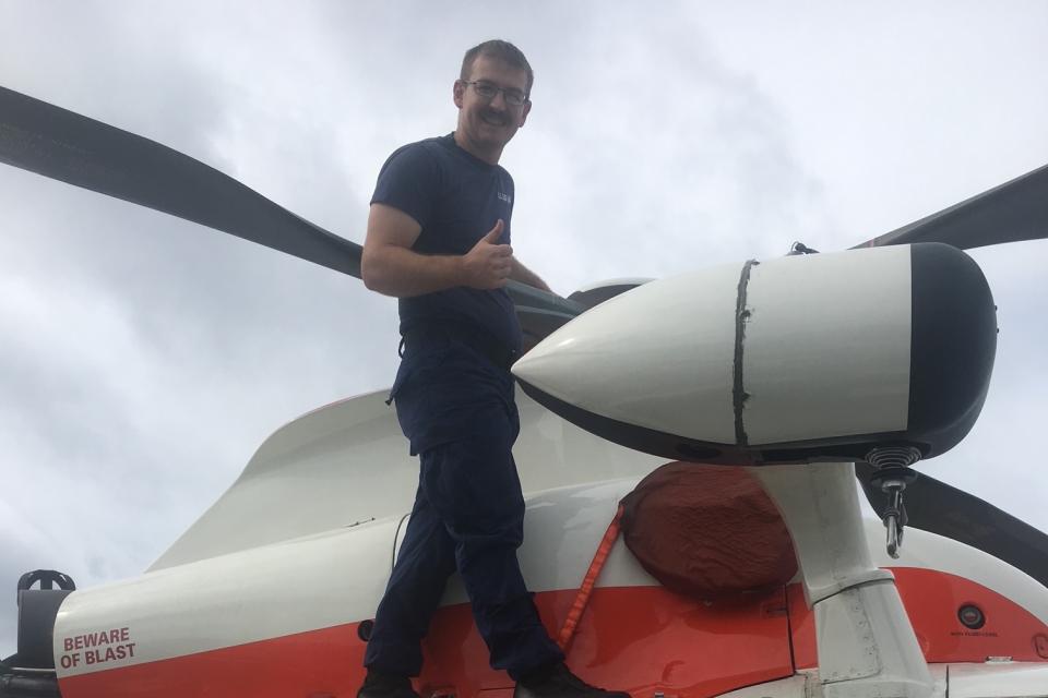 Person standing on top of a parked U.S. Coast Guard helicopter