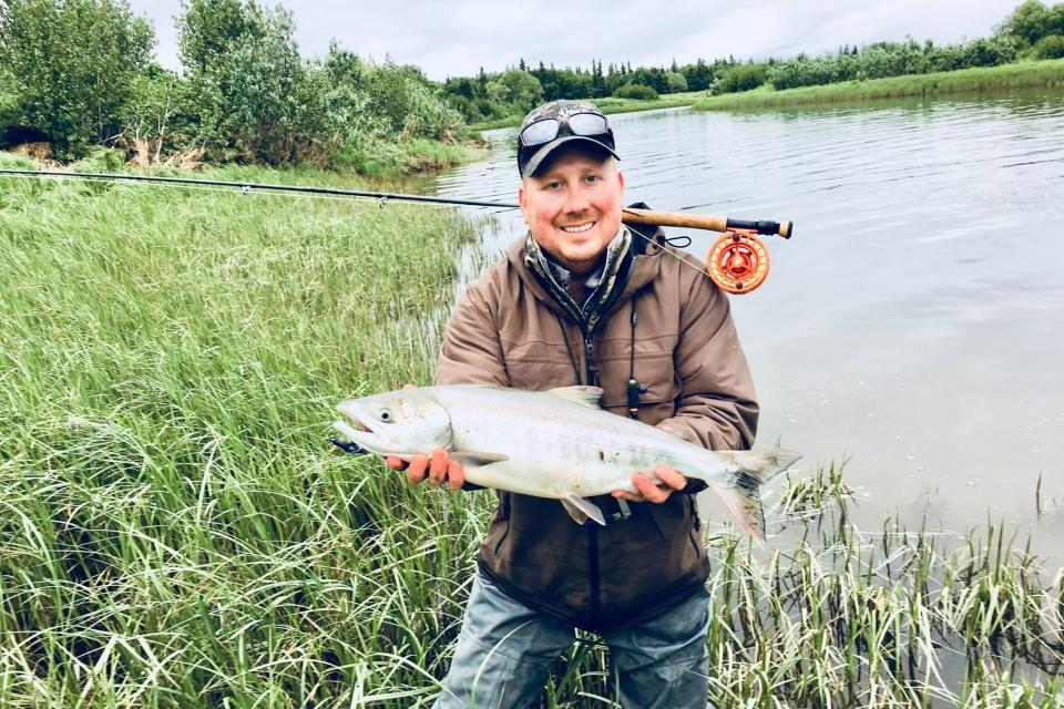 Man holding a fish next to a body of water