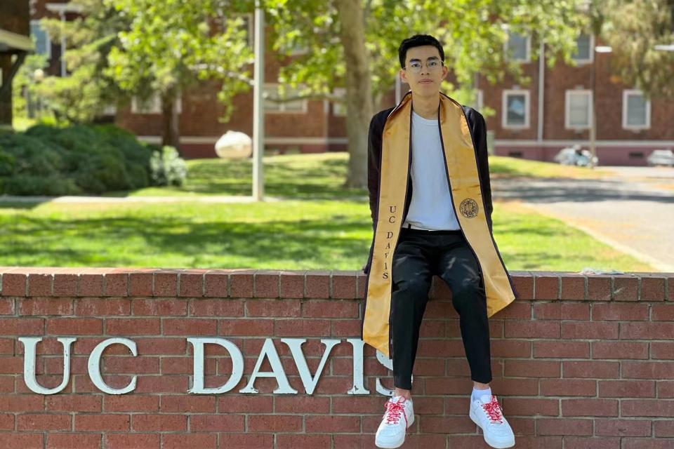 Shiwei Zhang sitting on a UC Davis sign