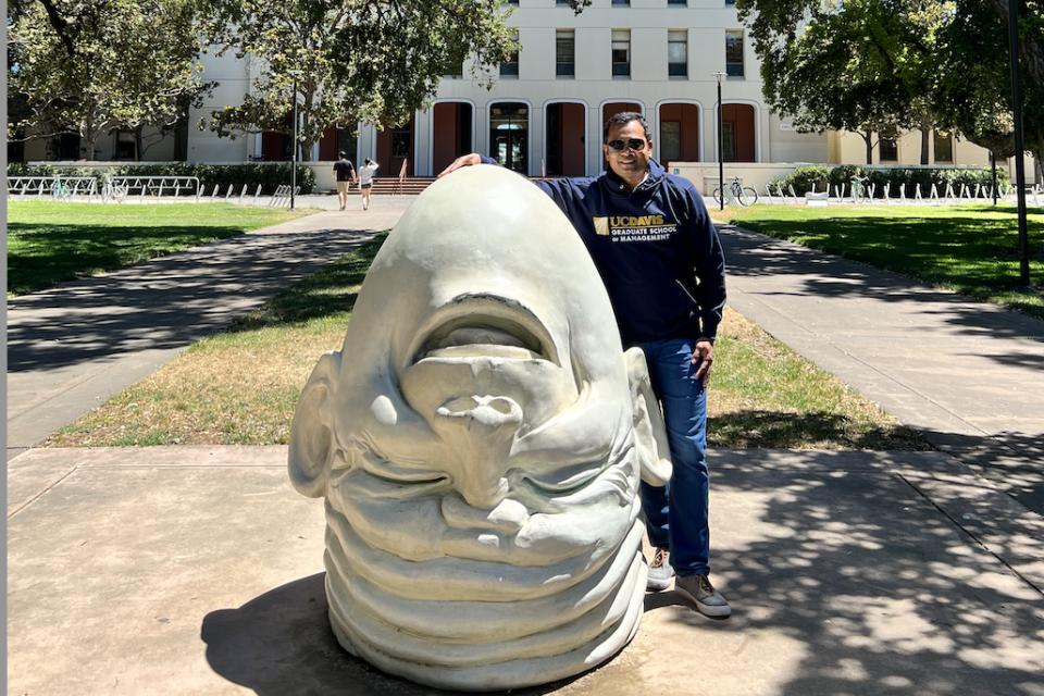 Debasish Panda at the UC Davis campus posing with an egghead sculpture