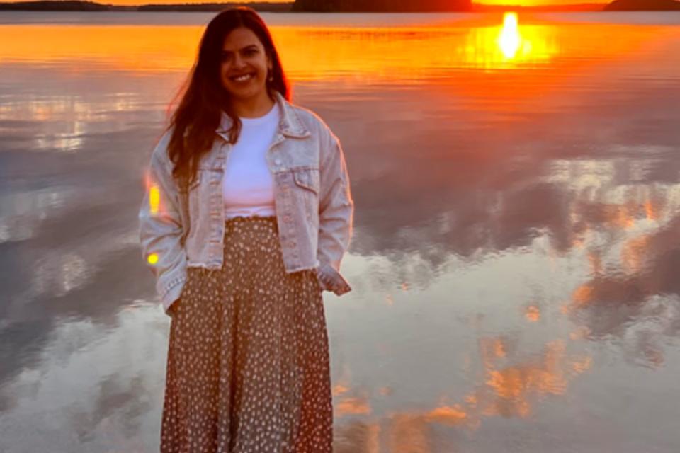Prachi Mishra standing in front of a lake at sunset