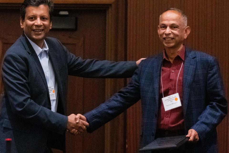 Distinguished Professor Hemant Bhargava (right) accepts the ISS President’s Service Award from Professor Indranil Bardhan