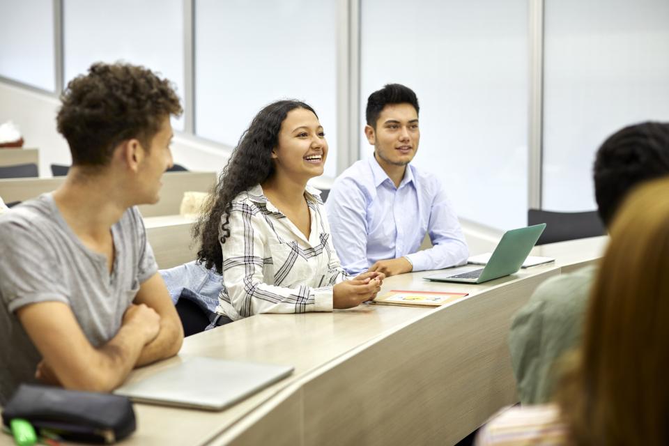 Three students sitting in a classroom smiling