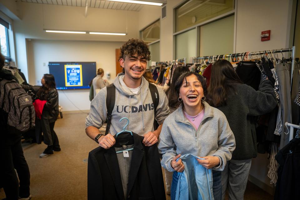 Two students holding up their finds at the Business Boutique Clothing Drive