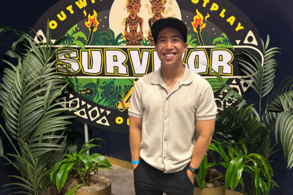 Kevin Leung in front of a banner that reads Survivor