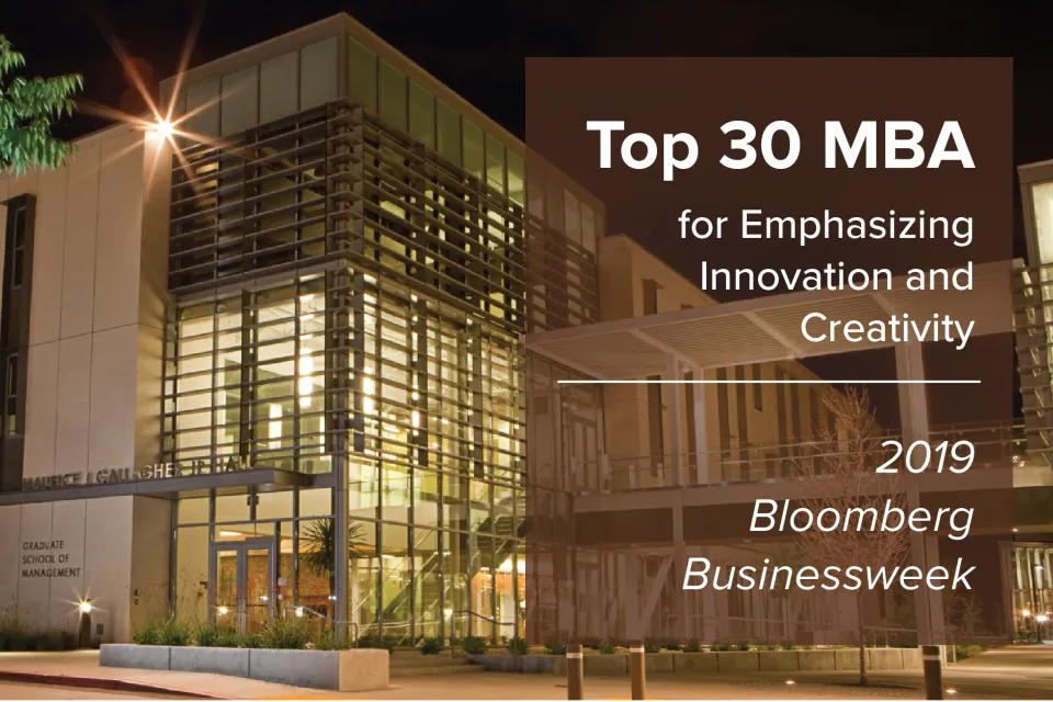 Modern university building at night with sign reading "Top 30 MBA for Emphasizing Innovation and Creativity, 2019 Bloomberg Businessweek.
